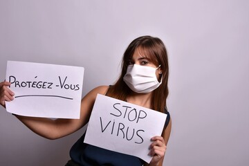 Femme avec un masque qui tient 2 affiches