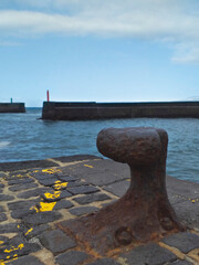 Rusty iron bollard on dock, harbor entrance and port and starboard signals. Nautical, ports and maritime navigation fund.