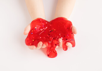 Red slime toy in kids hands on white background. Making slime. Top view. Flatlay
