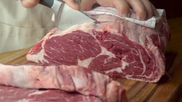 butcher slicing chunk of beef rib eye