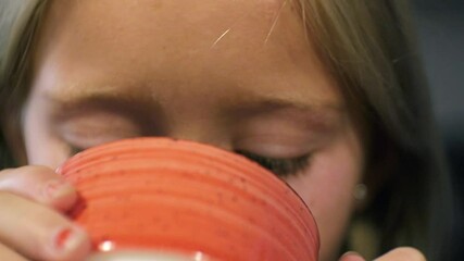 Close-up of laughing young girl drinking milk coffee leaving mustache on the upper lip.