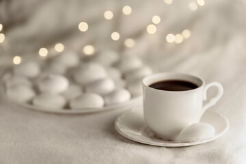 White cup of coffee with meringues on soft blanket.