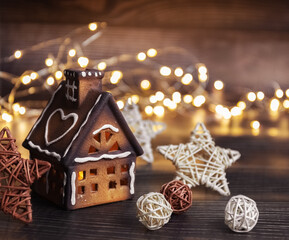 Obraz na płótnie Canvas Christmas gingerbread house on a dark background. Christmas lights, garland. Card. Copy space.