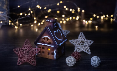 Christmas gingerbread house on a dark background. Christmas lights, garland. Card. Copy space.
