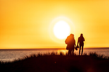 Silhouette of a group of four people standing at the hill on sunset
