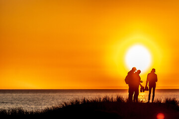 Fototapeta premium Silhouette of a group of four people standing at the hill on sunset 
