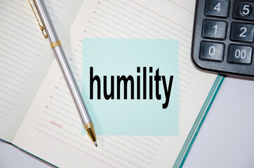 The word humility is written on a blue sticker that is glued to a notebook