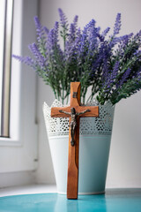 Wooden cross and lavender bouquet by the window
