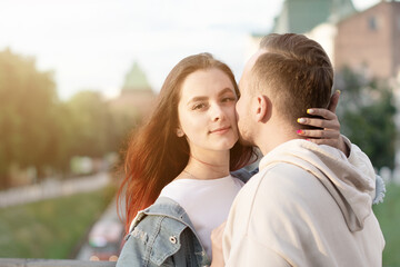 Fototapeta premium Happy young couple caucasian woman and man is sharing smile and walking in street summer. Concept couple in love. Female is hugging her husband. Family. Love.