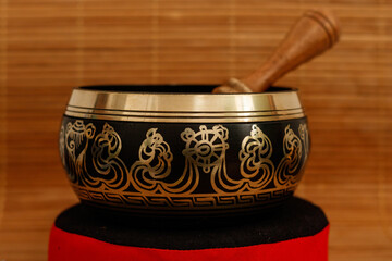 tibetan singing bowl with stick on wooden background, close up. 