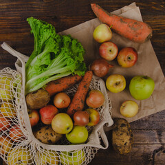Flat lay composition with meshed eco shopping bag. Organic fruits and vegetables in a cotton bag. Vegan, zero waste, plastic free, reusable concept