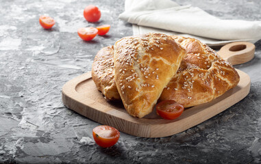 Uzbek samsa on a wooden Board. Uzbek samsa on a dark background with tomatoes