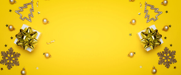 Fototapeta premium Gift boxes yellow. White gifts with golden ribbon, New Year balls and sparkling lights in Christmas composition on dark yellow background for greeting card. Xmas backdrop with space for text.