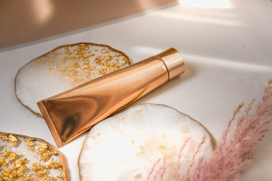 Golden cosmetic tube on pastel color minimalism beauty
