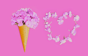 Closeup of cone with pink flowers as ice cream and heart shaped petals over background