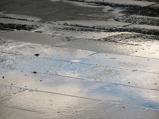 Reflection of the blue sky on the rain-soaked city square
