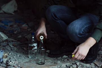 Young vandal protester makes a molotov's cocktail on the floor of abandoned building. Urban war.