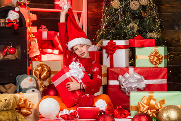 Obraz na płótnie Canvas fastest gifts delivery. everyone will get a present. post full of present boxes and parcels. small teenage boy after shopping. child in red santa hat. childhood is the best time. dreams come true