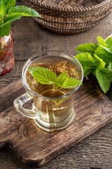 A cup of melissa tea with fresh melissa plant