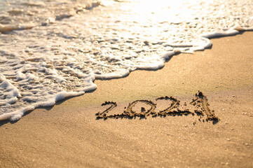 Sandy beach, sea wave and the inscription 2021. New Year 2021 Concept