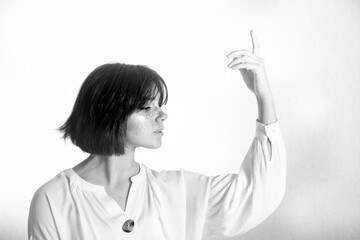 Girl with short hair in a white blouse with a raised hand isolated on a white background.