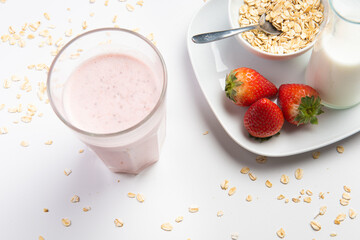 strawberry cereal cocktail for breakfast in a glass cup on a white plate with ingredients. shooting from top to bottom. flat composition.