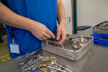  employee of a hospital sterilization department sorts the cleaned instruments into a container