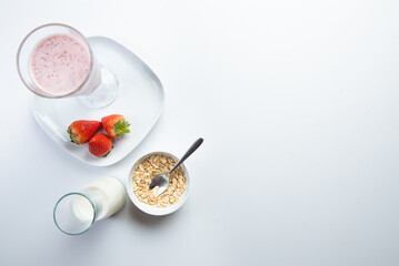 strawberry cereal cocktail for breakfast in a glass cup on a white plate with ingredients. shooting from top to bottom. flat composition. with free space for text, labels and logos