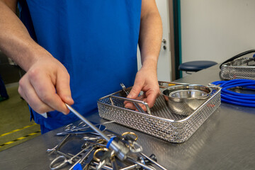  employee of a hospital sterilization department sorts the cleaned instruments into a container