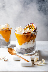 Healthy tropical fruit chia pudding with granola, mango, passion fruit and coconut chips in a glass jar. Vegan healthy breakfast, clean eating.