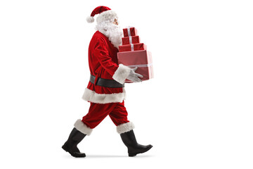 Full length profile shot of a santa claus walking and carrying a pile of christmas presents