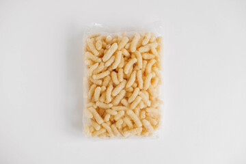 Corn sticks in a plastic bag on a white background. Top view. Copy, empty space for text