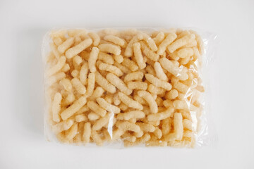 Corn sticks in a plastic bag on a white background. Top view. Copy, empty space for text