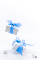 Christmas composition. White gift box with blue ribbon, New Year balls in xmas composition on white background for greeting card. Christmas, winter, new year concept.