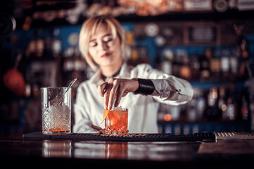 Portrait of girl bartender demonstrates the process of making a cocktail