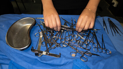 Manos de mujer manipulando instrumental quirúrgico sobre mesa con tela azul