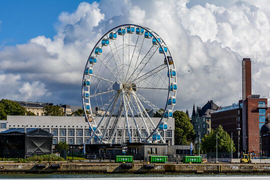 Helsinki, Finland - August 24, 2020: Tall Ferris wheel called Helsinki SkyWheel rising above the harbour. One of its gondola cabins, the SkySauna, is the world's first sauna on a Ferris wheel.