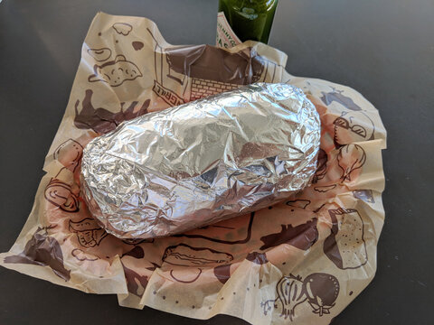 Chipotle Mexican Grill burrito wrapped in tin foil in a basket