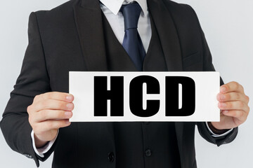 A businessman holds a sign in his hands which says HCD - HUMAN CENTERED DESIGN