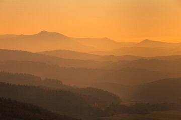 Mountains colored in shades of orange at sunset in autumn..The ridges of the mountains are condensed from the perspective of a telephoto lens.