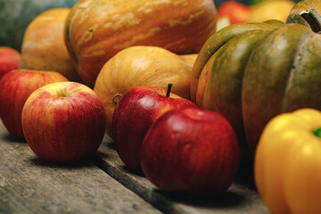 Pile of red apples and pumpkins on wooden surface