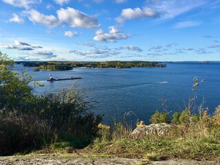 A big ferry slowly moving across the water - or the Swedish lake Mälaren(Malar or Malaren). Sunny day with nice weather. Great view from a small mountain or hill. Gåseborg, Görväln, Stockholm Sweden.