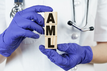 The doctor holds cubes in his hands on which it is written - AML. Acute Myeloid Leukemia