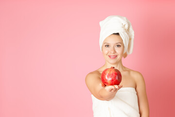 mock up, a ripe pomegranate on the palm of a young woman in defocus on a pink background
