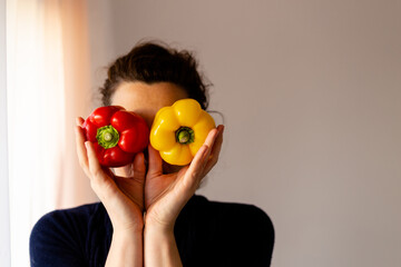 Woman holding fresh red and yellow pepper like binoculars