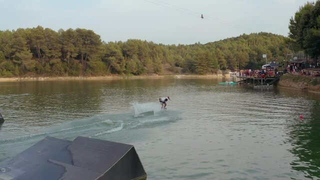 Extreme sports athlete wake boarding doing a tricks on nautical lift, wake skating, big spine in wake skate
