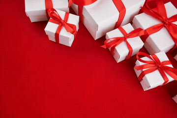 White gift box with red ribbon bow, isolated on red. Christmas gifts presents on red background. Simple, classic red and white wrapped gift boxes with ribbon bows. Merry Christmas. Happy New Year.