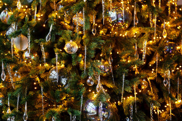 texture or background for a holiday card. Christmas tree in the apartment. green branches of Christmas decorations balls. bright garland of yellow light bulbs.