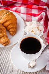 delicious fresh croissant and cup of coffee on a white wooden rustic background