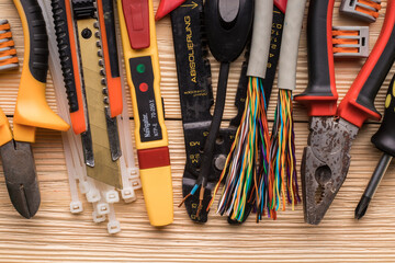 Tools for electrical installation, multi colored electrical cables, terminals and ties on a wooden...